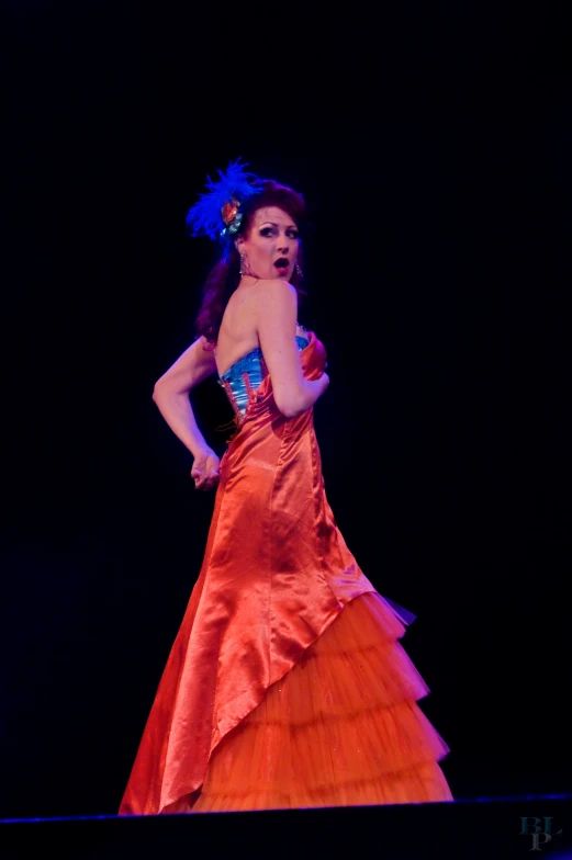 a lady dressed in an orange dress with flowers on top