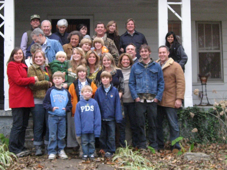 a group of people are posing outside the house