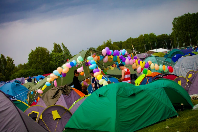 many tents are set up outside under colorful balloons