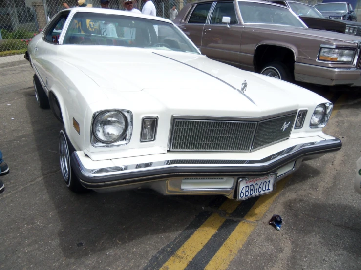 an old white car is parked in the parking lot