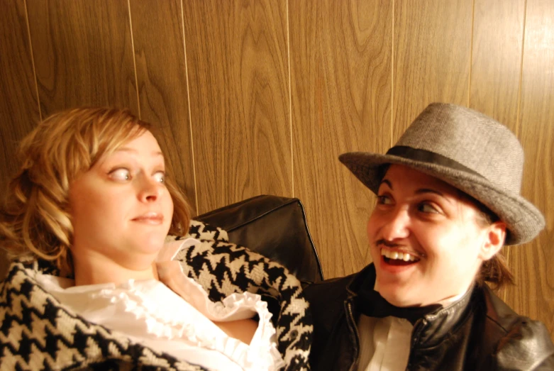 a man sitting next to a woman wearing a hat