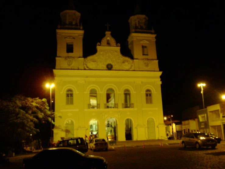 a large church with a tower and car parked in front