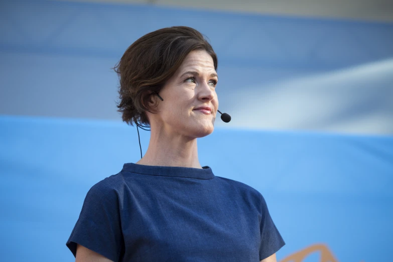 a woman speaking to an audience with headphones on