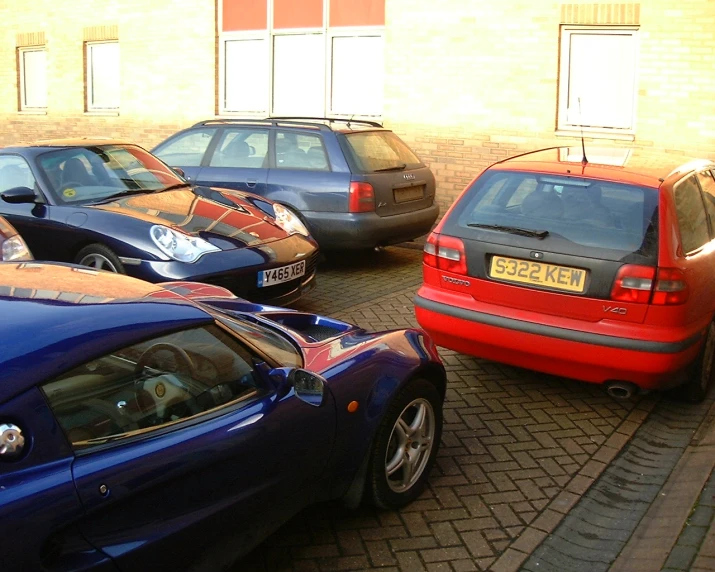 a couple of cars parked next to each other on a cobblestone area