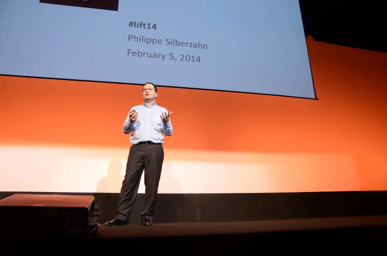 man giving presentation during a conference in front of a large screen