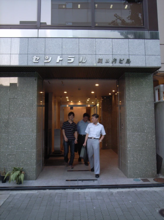 two men in front of a el while one looks on