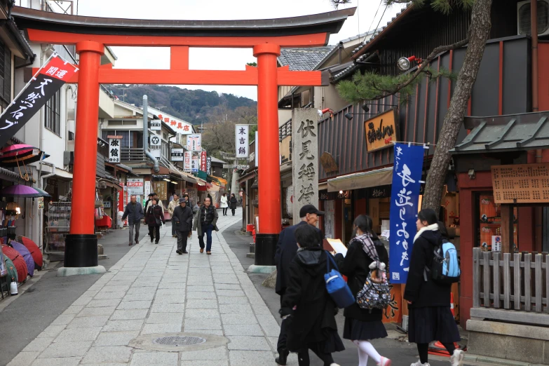 a group of people walking down a sidewalk under a gate