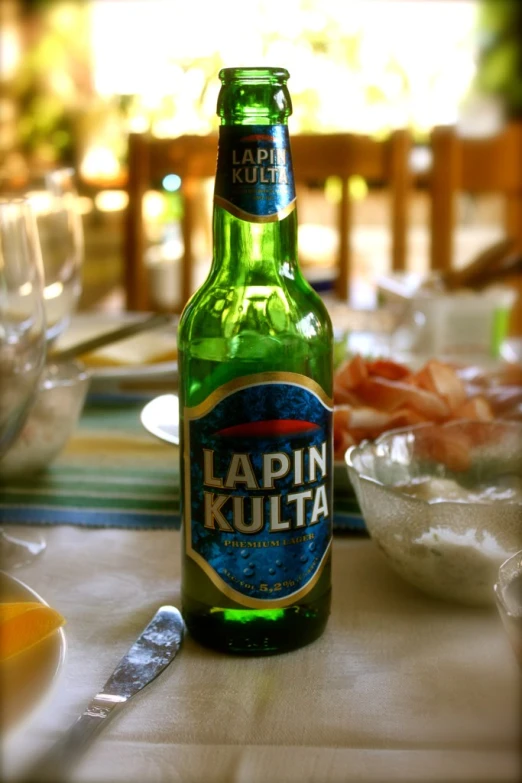 a bottle of lapin kulta is sitting next to two bowls and silverware
