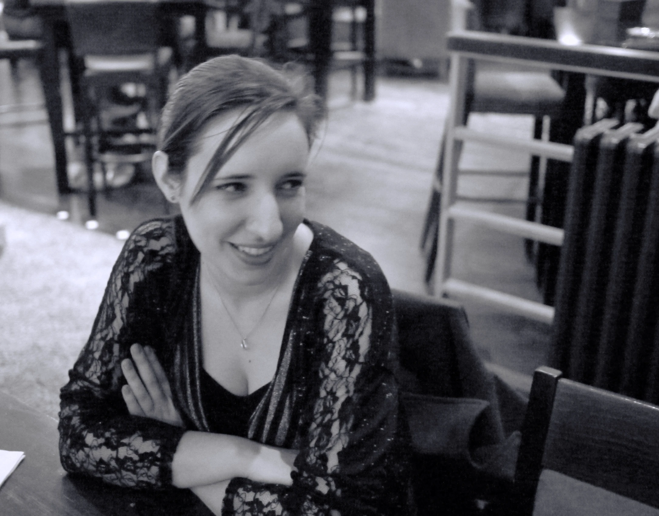 a woman with her arms crossed posing at the end of a restaurant table