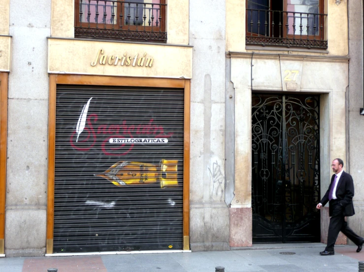 a man walking past a closed up garage door