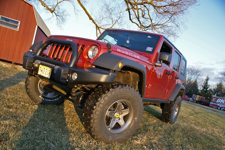 a red jeep with front bumper is parked on the grass