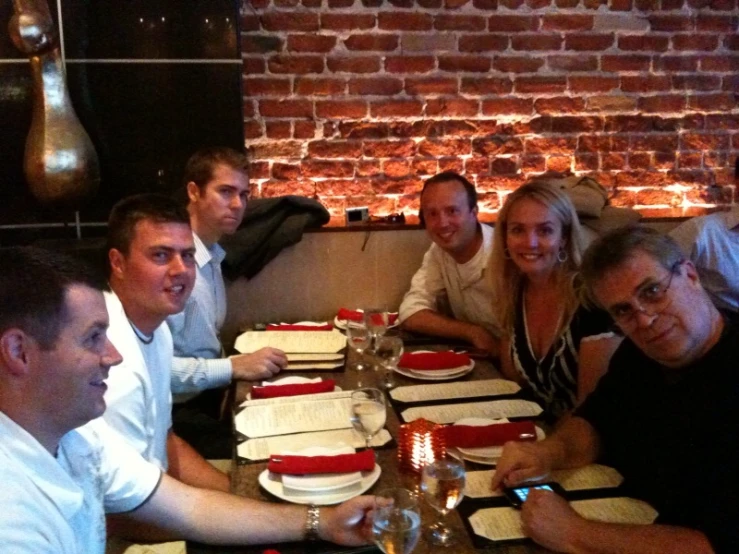 a group of people are posing for a picture while having dinner