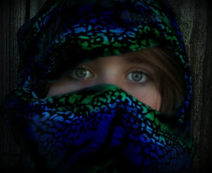 a woman's eyes are shining through her blue scarf