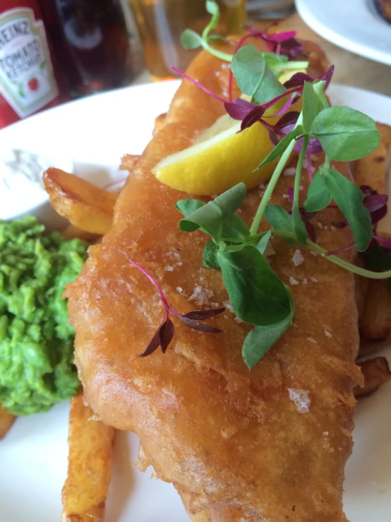 a dinner plate has fish, pea and lemon on it