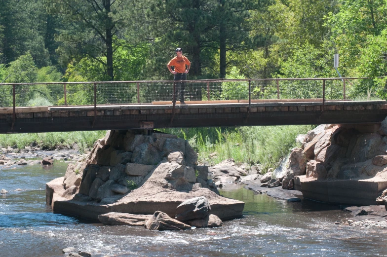 a man stands on the edge of a bridge over water