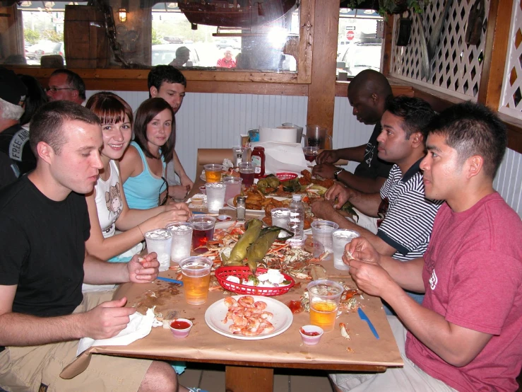 a group of friends sitting at a dinner table with plates and glasses in front of them