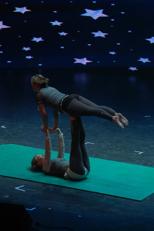 a couple of dancers doing a handstand on a mat