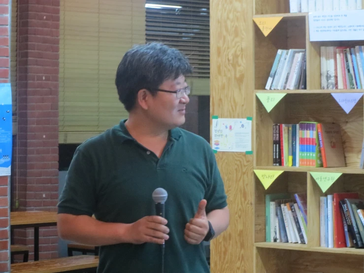 a man holding a microphone stands in front of bookshelves