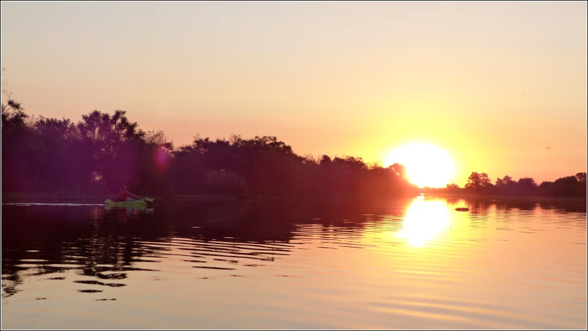 canoes are on the water in a setting sun