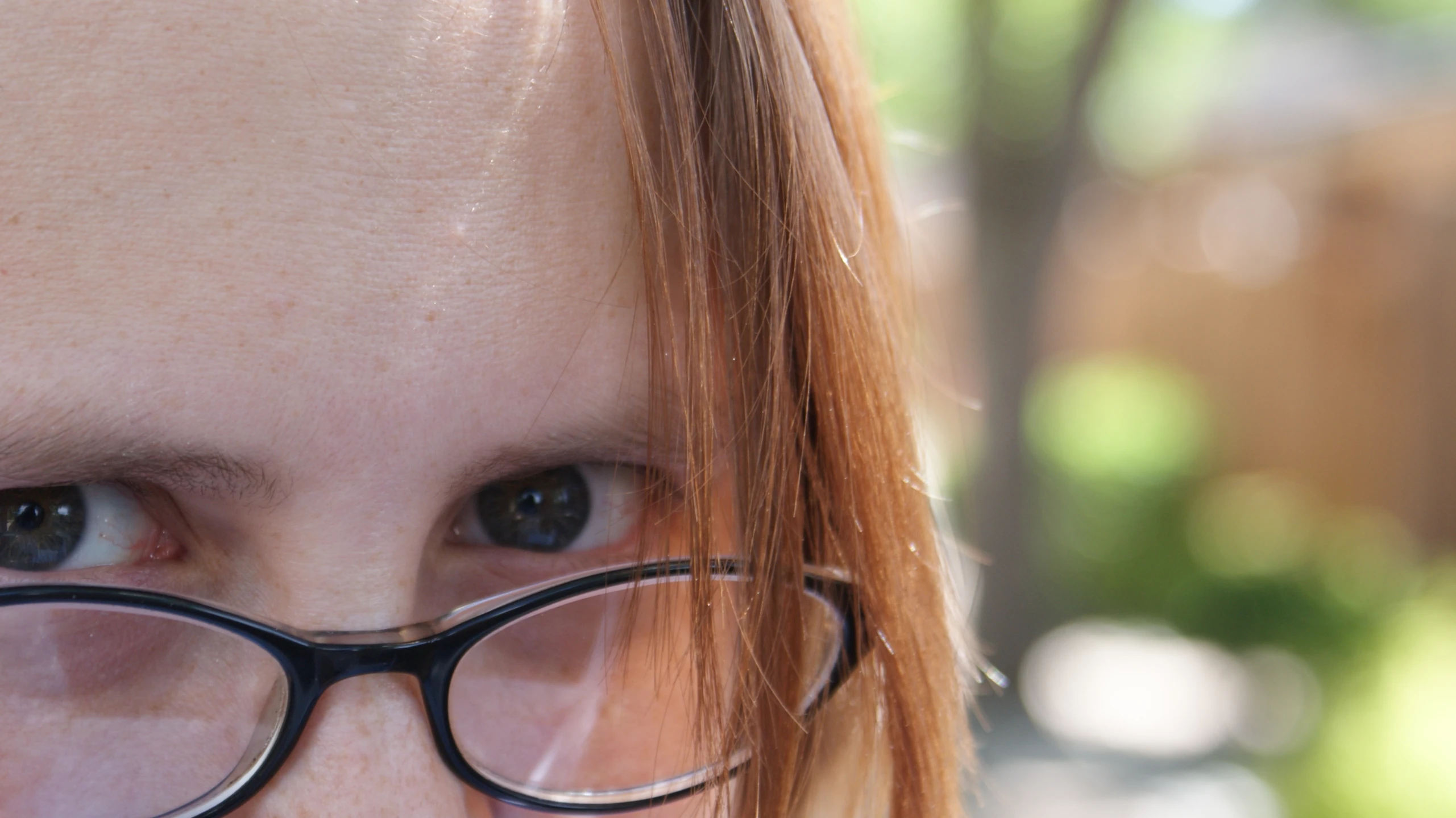 a red headed woman wearing glasses looking at the camera