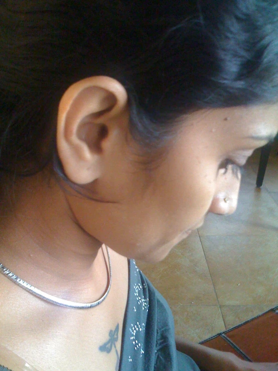 a woman is wearing a silver necklace on her neck