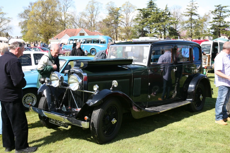 an antique car sits parked on the grass