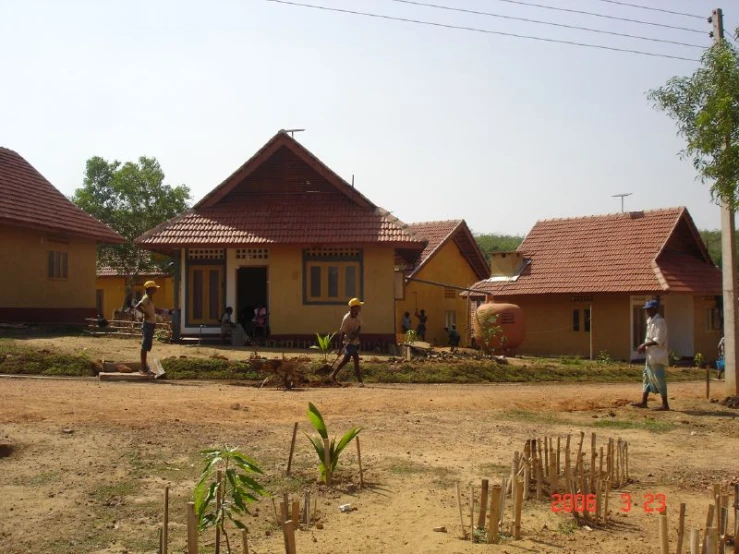 people on dirt road next to small houses