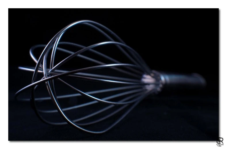 a wire whisk with several attachments, on a black background