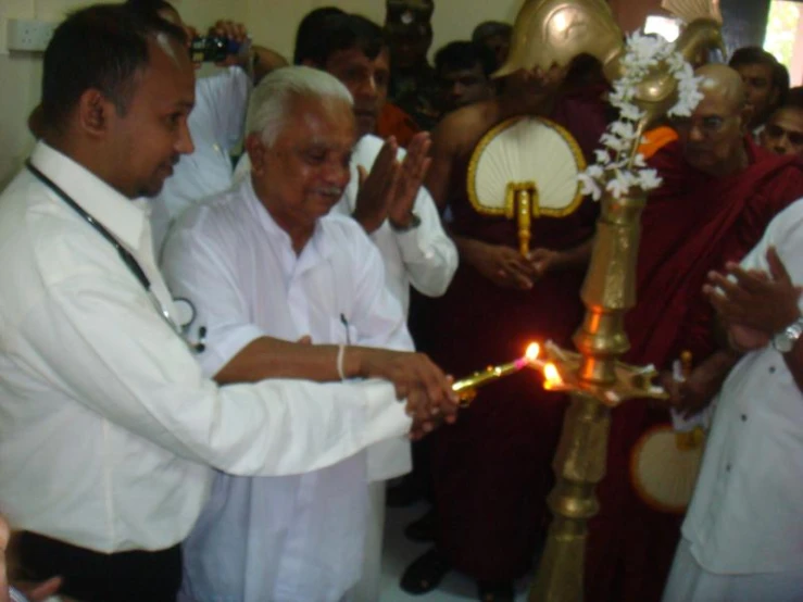 people are holding candles and standing around