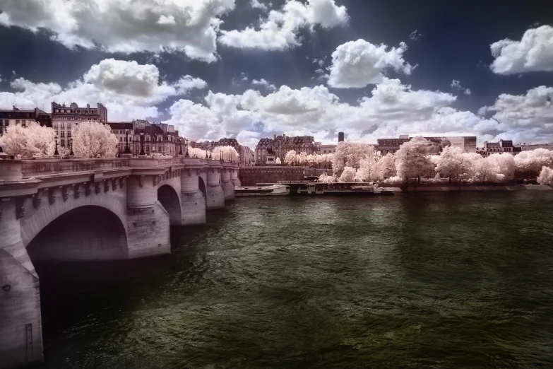 a view of the water, a bridge and buildings on a cloudy day