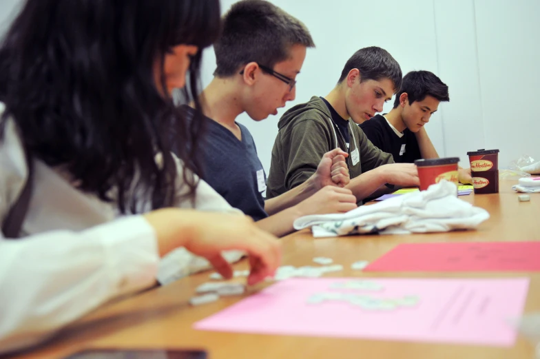 four people sitting at a table working on project