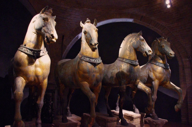 three statues of horses standing in front of an arch