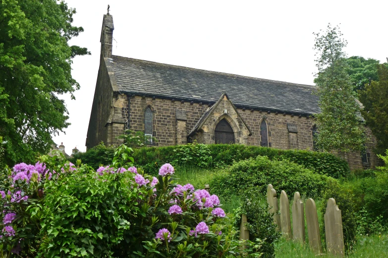 the front of an old church surrounded by lush green shrubs