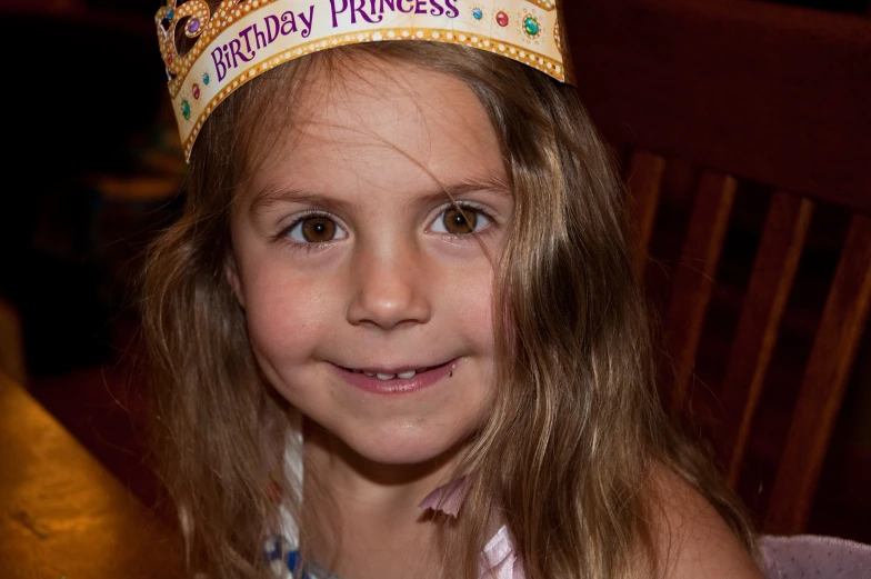 the little girl has a birthday crown on her head