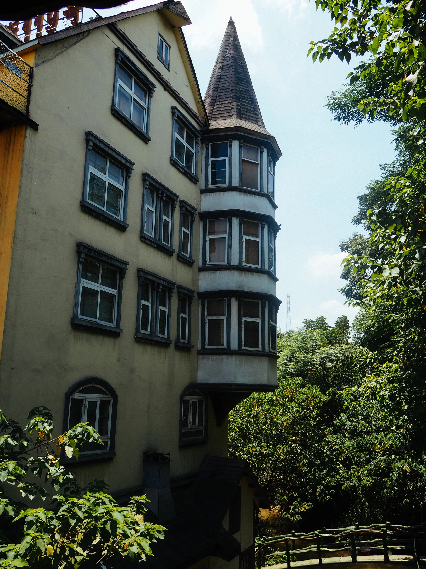 a building with three stories and a spire in front of trees