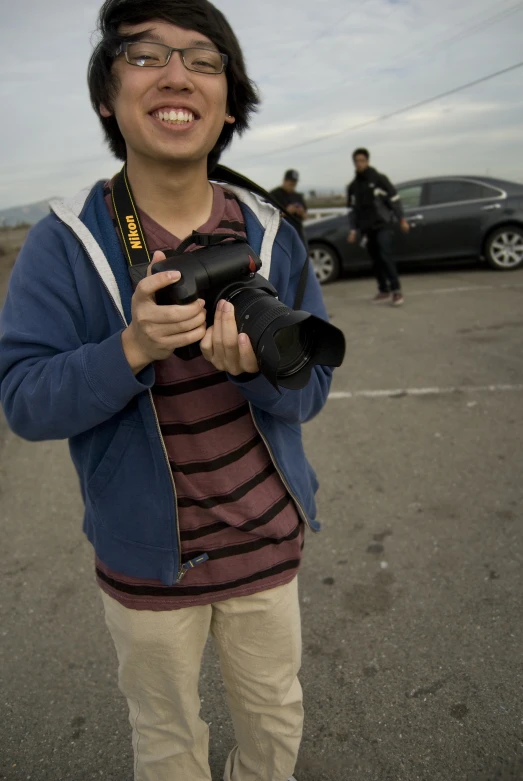 a man in the middle of an asphalt parking lot while taking a pograph of a person