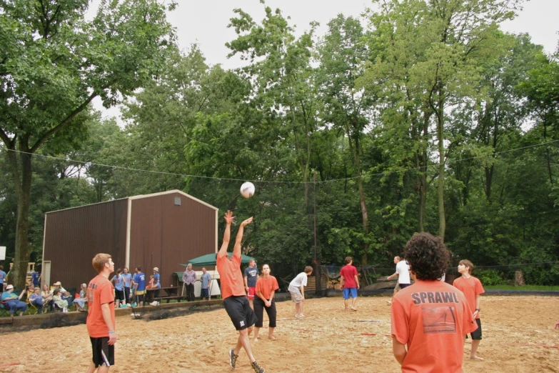 two boys trying to block another while playing volleyball