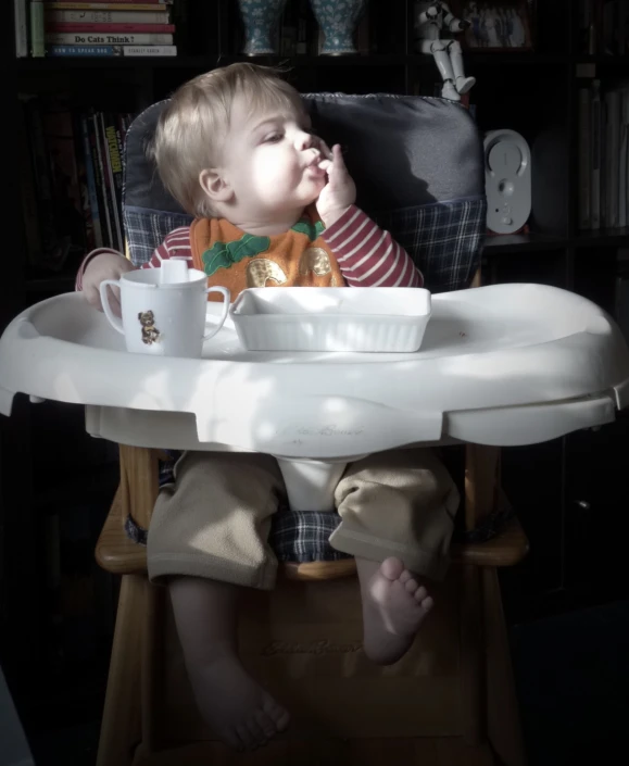 a small child is eating food in the high chair