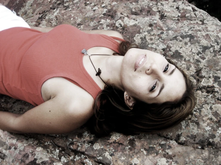 young woman laying on the rocks alone in the sunlight