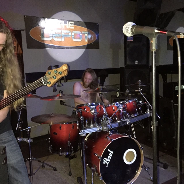 a girl and guy playing bass guitars in front of some microphones