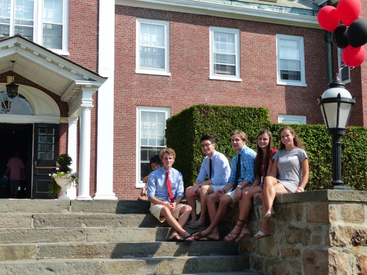 four children are sitting on steps in front of a building