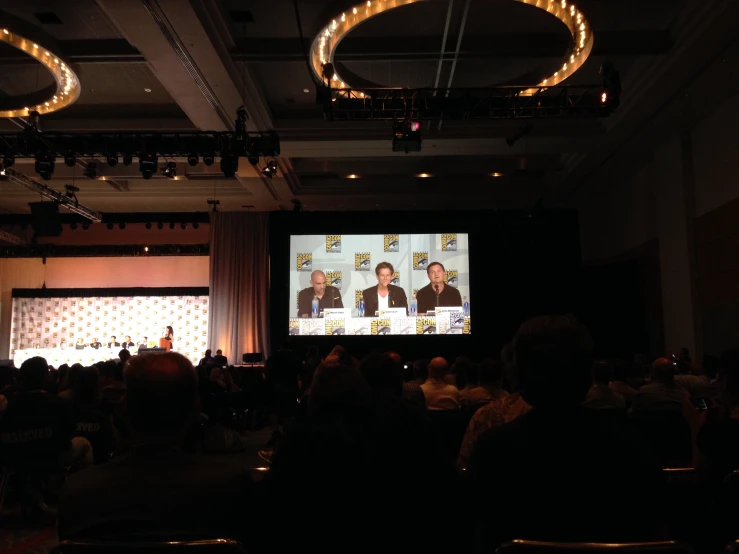 a big screen with people watching it during a debate