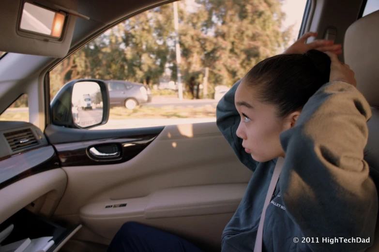 a young lady is sitting in the driver's seat of a car