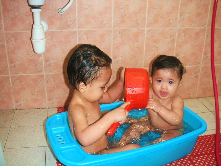 two young children sitting in an in - tub, playing with a toy