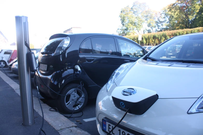 two electric cars plugged in to a public charging station