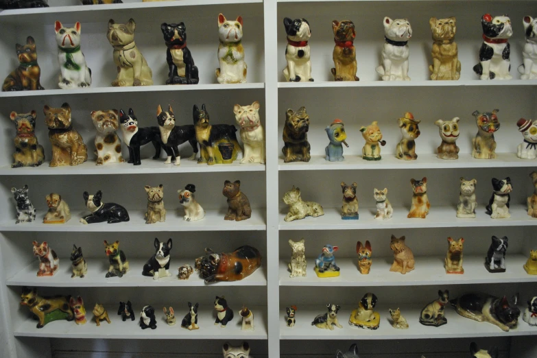 a collection of small animal figurines sit on a bookcase