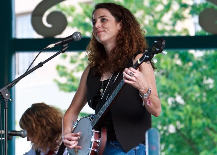 a woman playing an instrument while singing into a microphone