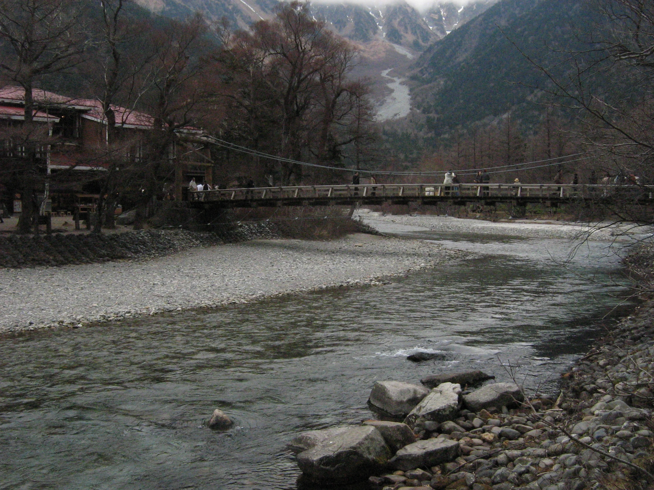 a small stream near a red building and mountains