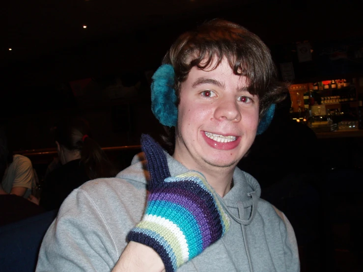 the boy smiles as he wears his mittens and holds the gloves