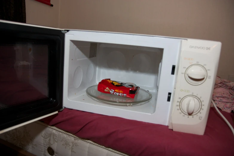 a microwave with a chocolate car inside is on the bed